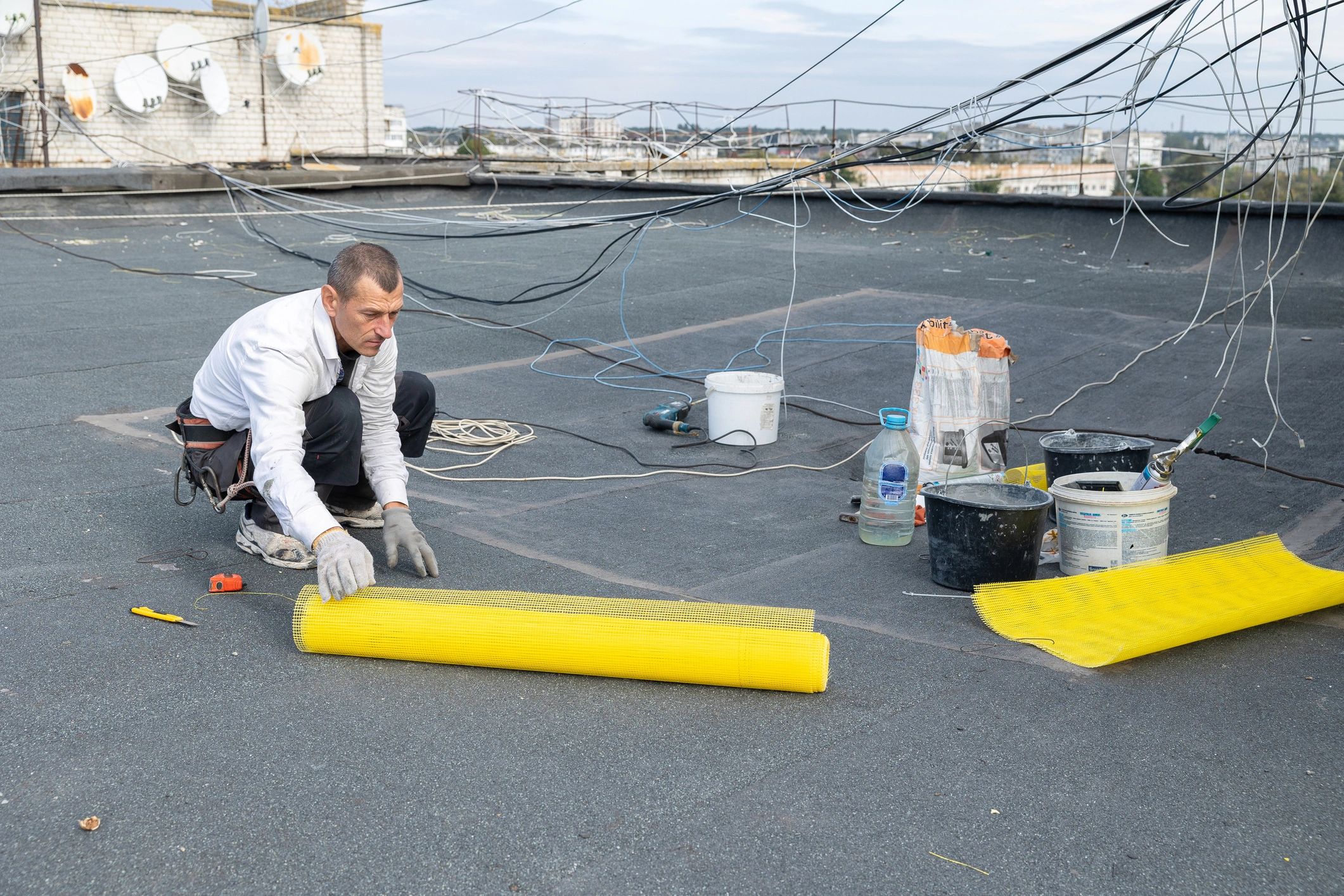 Worker on a residential roof preparing materials for repair